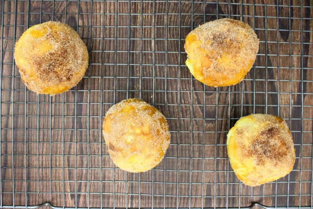 brush peach biscuit bombs with butter and dip in cinnamon sugar