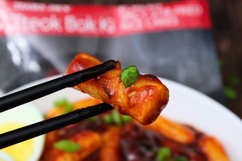 holding up a piece of air fryer tteokbokki with chopsticks