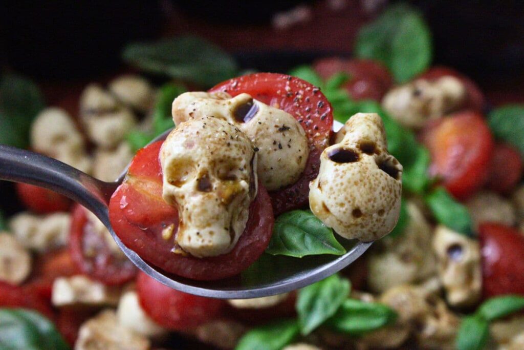 holding up a spoonful of halloween skull caprese salad