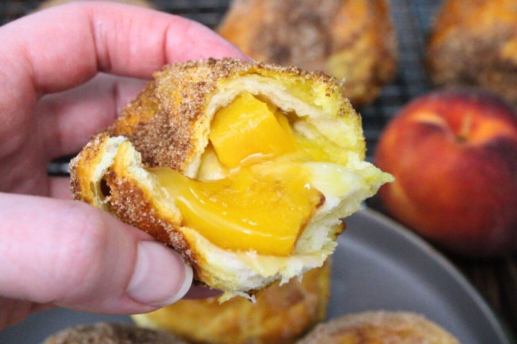 holding up half of a peach pie biscuit bomb to show the insides