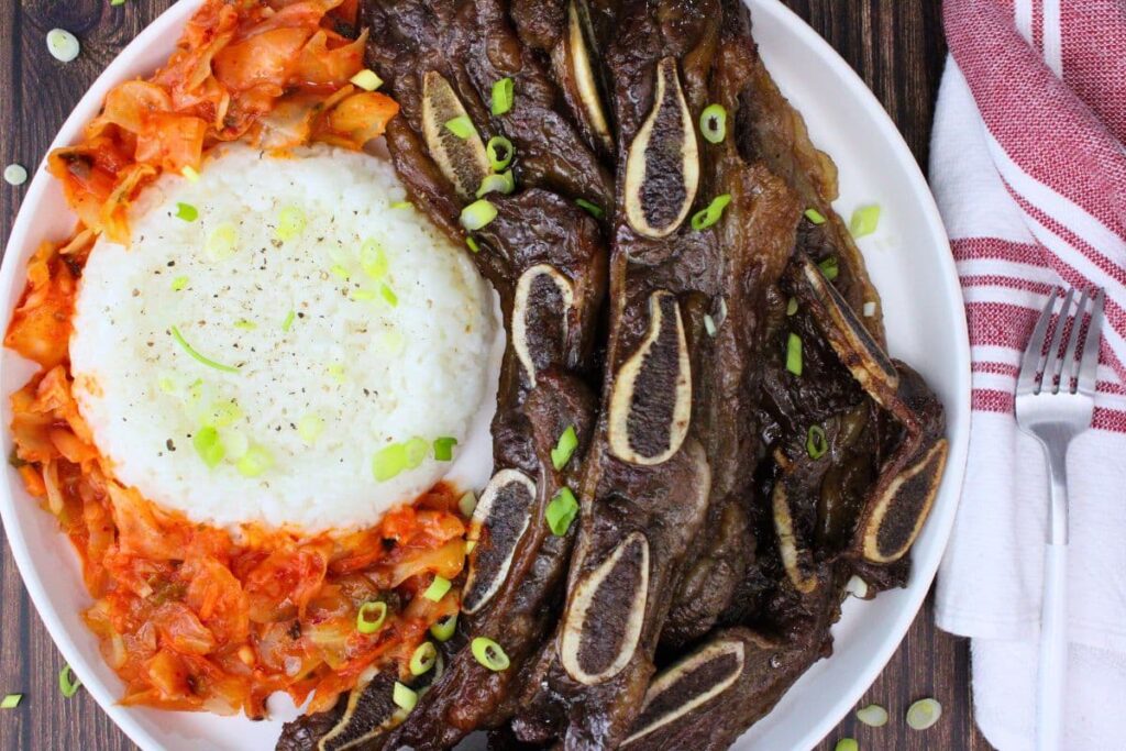 overhead view of air fryer trader joes beef korean short ribs on a plate with rice and kimchi