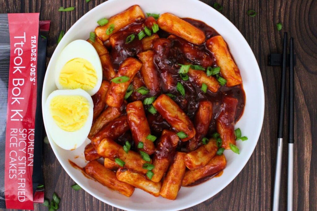 overhead view of air fryer tteokbokki with a sliced hard boiled egg and chopsticks to the side