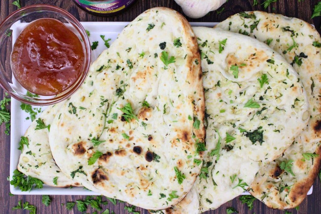 overhead view of several pieces of trader joes garlic naan on a platter with mango chutney