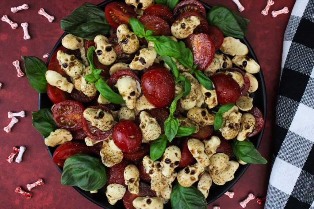 overhead view of skull caprese salad on a table next to a checkered napkin