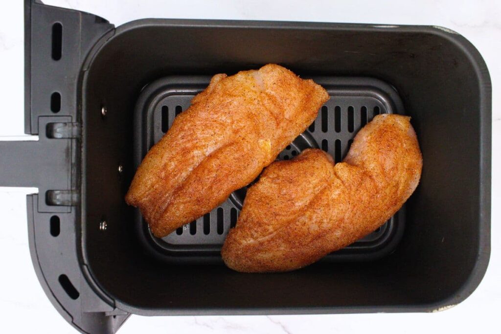 place seasoned chicken face down in air fryer basket