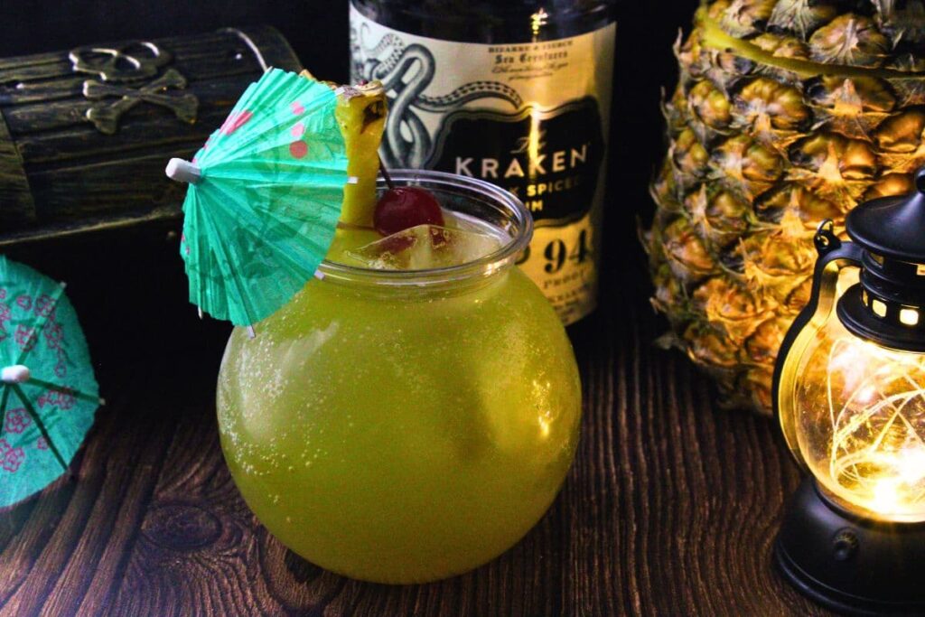 drunken pirate drink with cocktail umbrella in front of rum bottle and pineapple