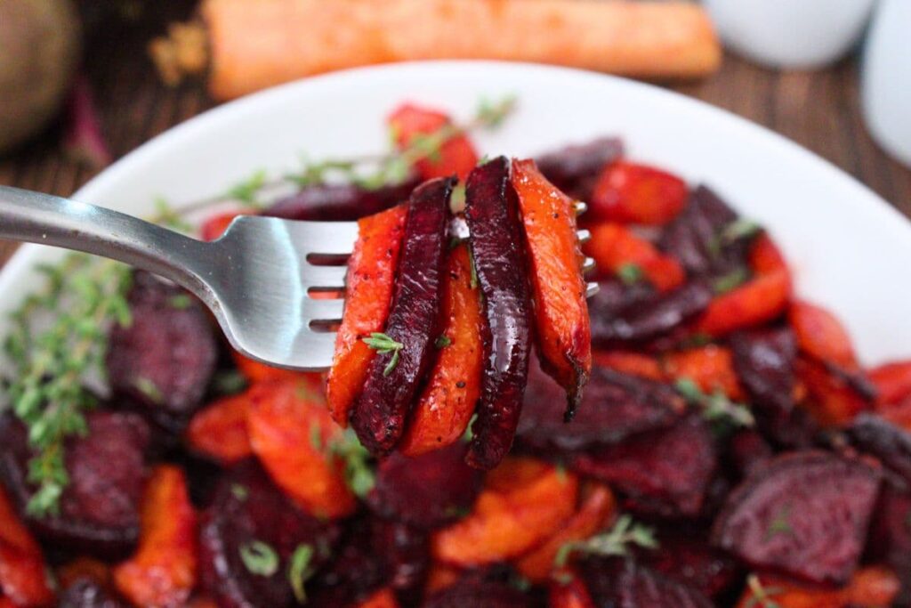 holding up a fork with slices of honey roasted air fryer beets and carrots