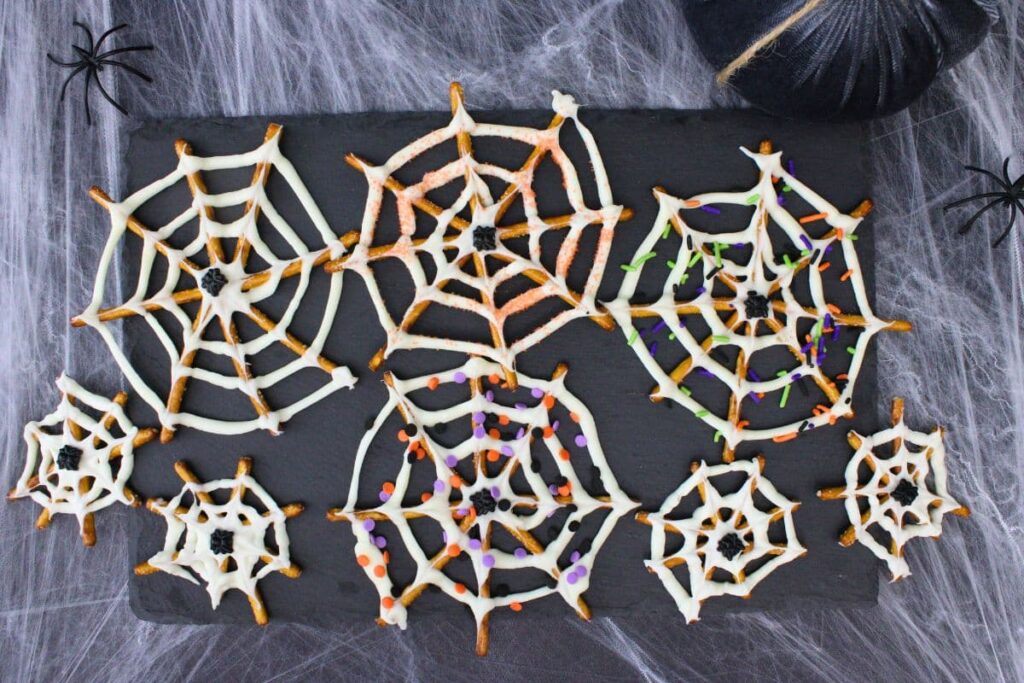overhead view of chocolate spider web pretzels on a spooky halloween background