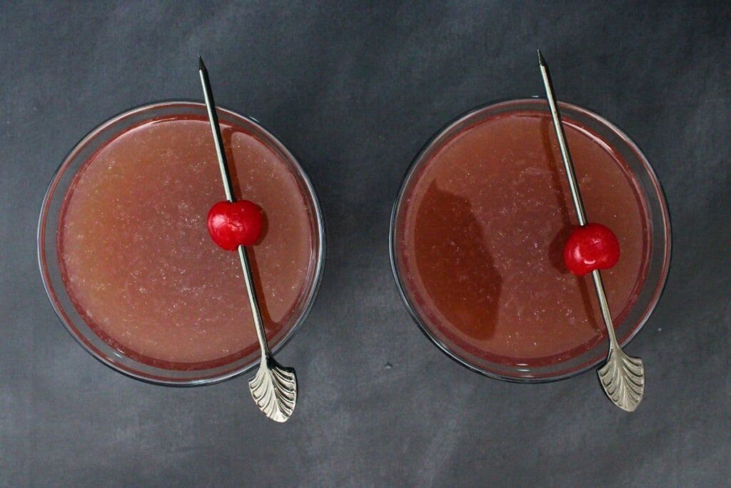 overhead view of two witch's heart cocktails garnished with cherries