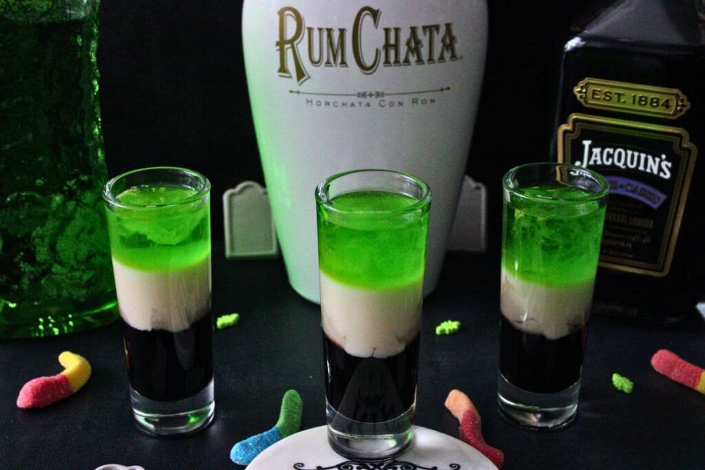 three beetlejuice shot drinks in front of liquor bottles