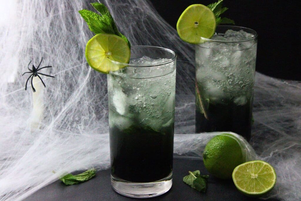 two black mojito drinks against a spooky spiderweb halloween background
