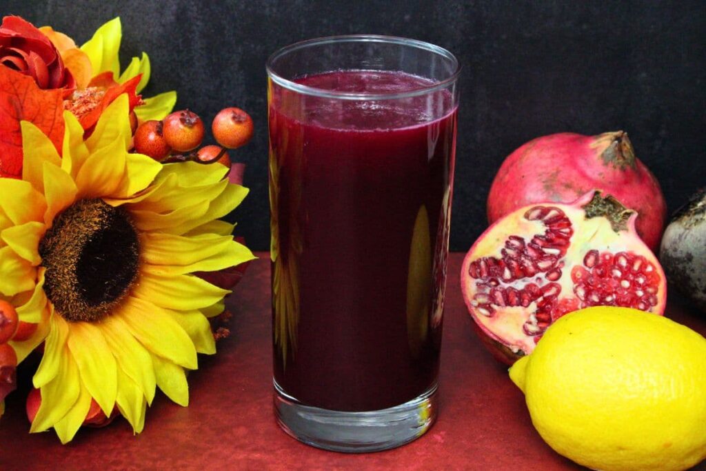 beetroot pomegranate lemonade surrounded by fresh fruit and flowers