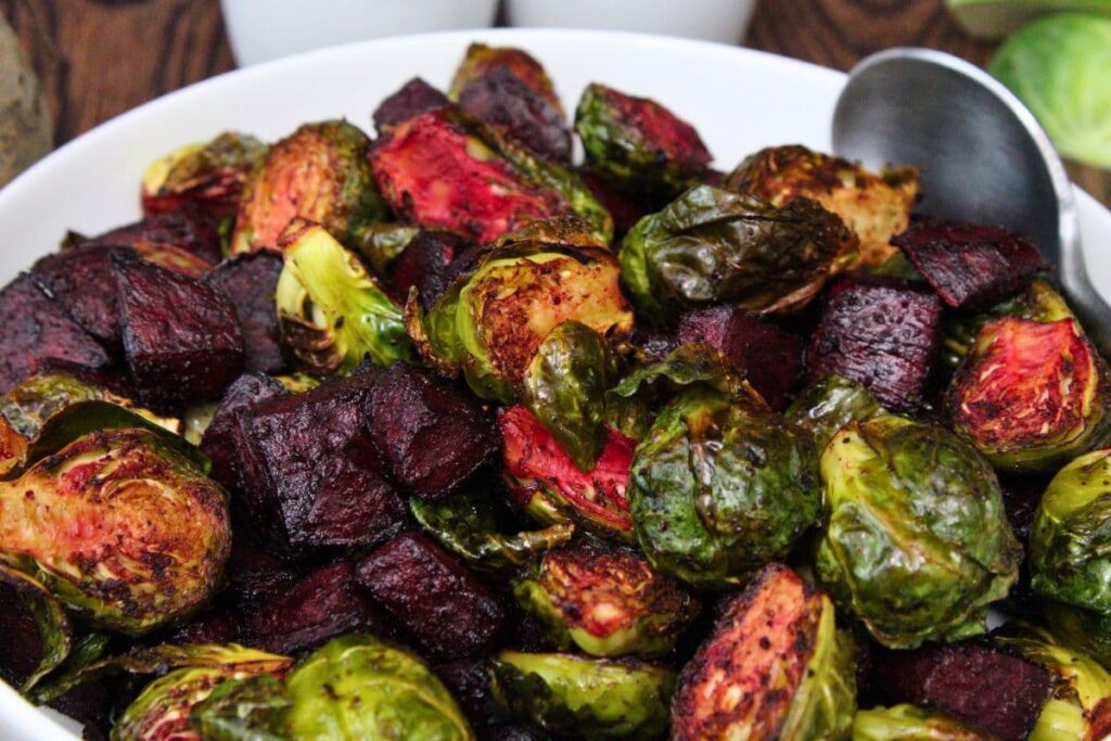 closeup view of air fryer roasted beets and brussels sprouts in a shallow bowl