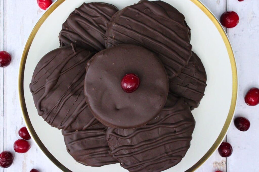 overhead view of chocolate covered cranberry sauce slices on a plate surrounded by fresh cranberries