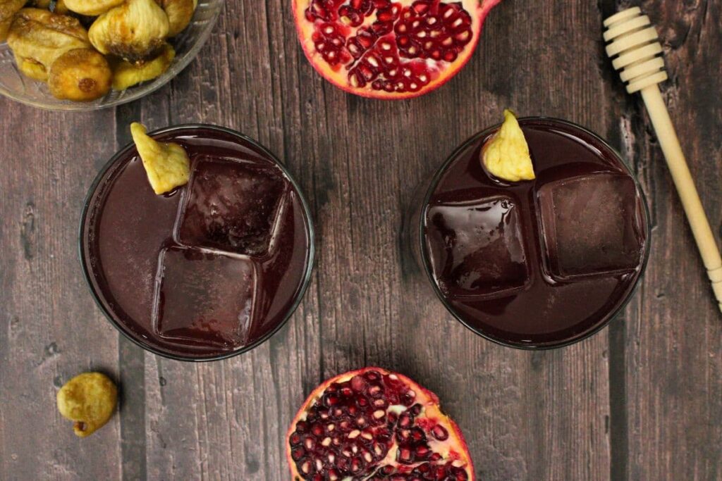 overhead view of two gladiator movie cocktails with fresh fig and pomegranate