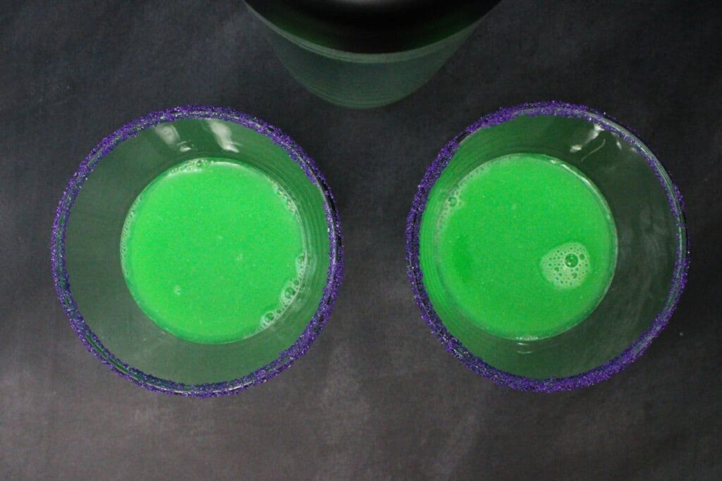 shake and strain wicked witch cocktail into prepared martini glasses