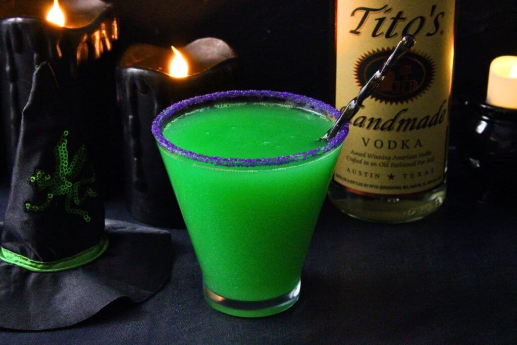 wicked witch cocktail in front of vodka bottle and next to witch hat