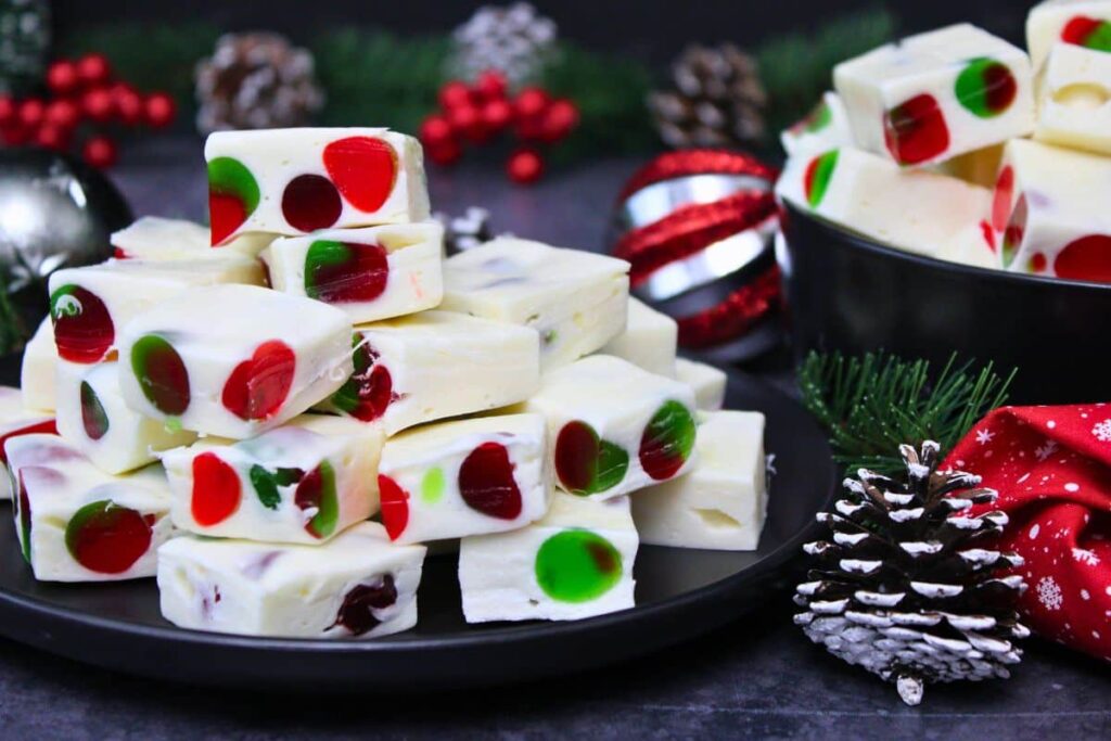 a plate stacked with marshmallow nougat squares next to a bowl filled with more nougat in a holiday setting