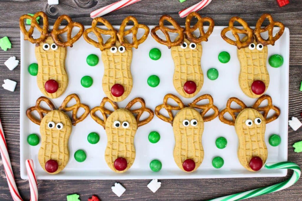 overhead view of eight nutter butter reindeer cookies on a square platter with m&m sprinkled around