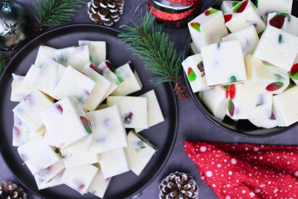 overhead view of marshmallow nougat stacked on a plate and in a bowl surrounded by holiday decorations