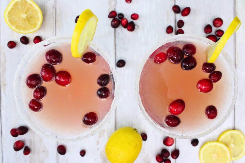 overhead view of two cranberry lemon drop martini cocktails with fresh cranberry and lemon