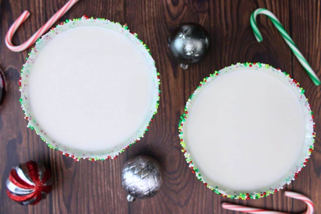 overhead view of two sugar cookie martini drinks with candy canes and ornaments