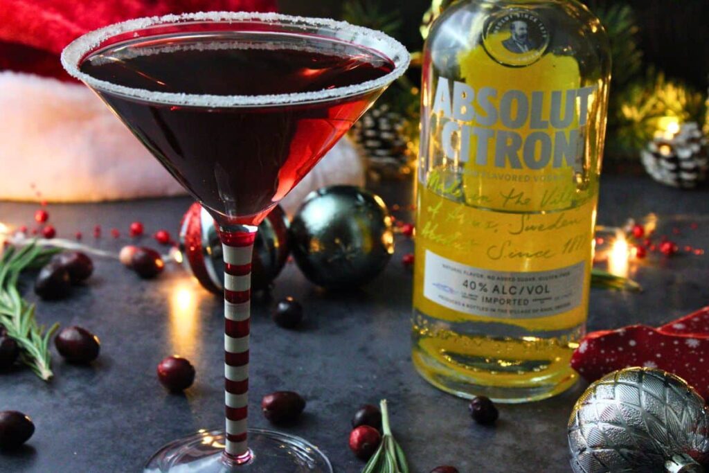 santa clausmopolitan cocktail next to vodka bottle in holiday setting with santa hat