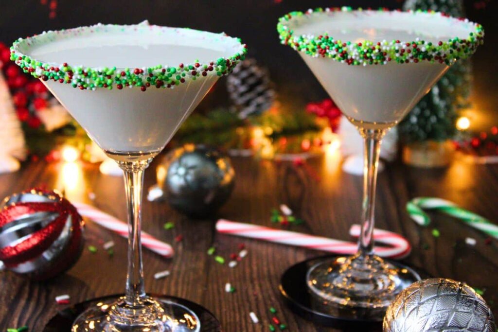 two sugar cookie martini cocktails surrounded by christmas lights, ornaments, and candy canes