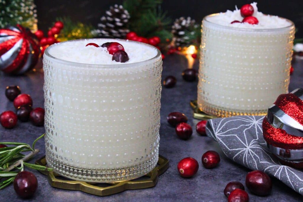 two white christmas punch cocktails with cranberries and shredded coconut
