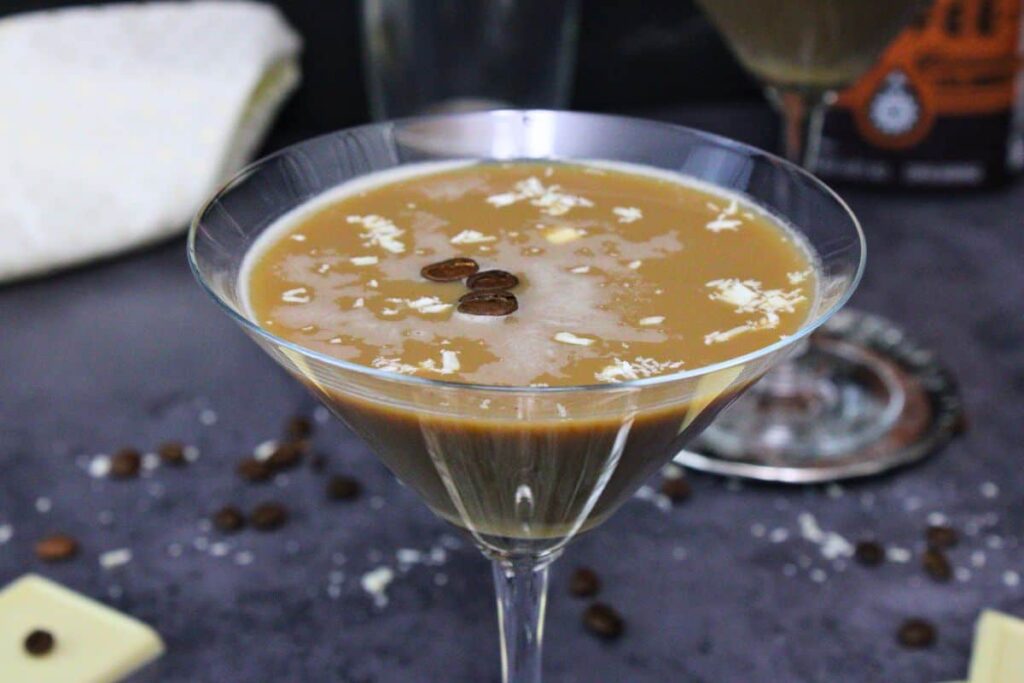 closeup of white chocolate espresso martini with three beans and shaved white chocolate