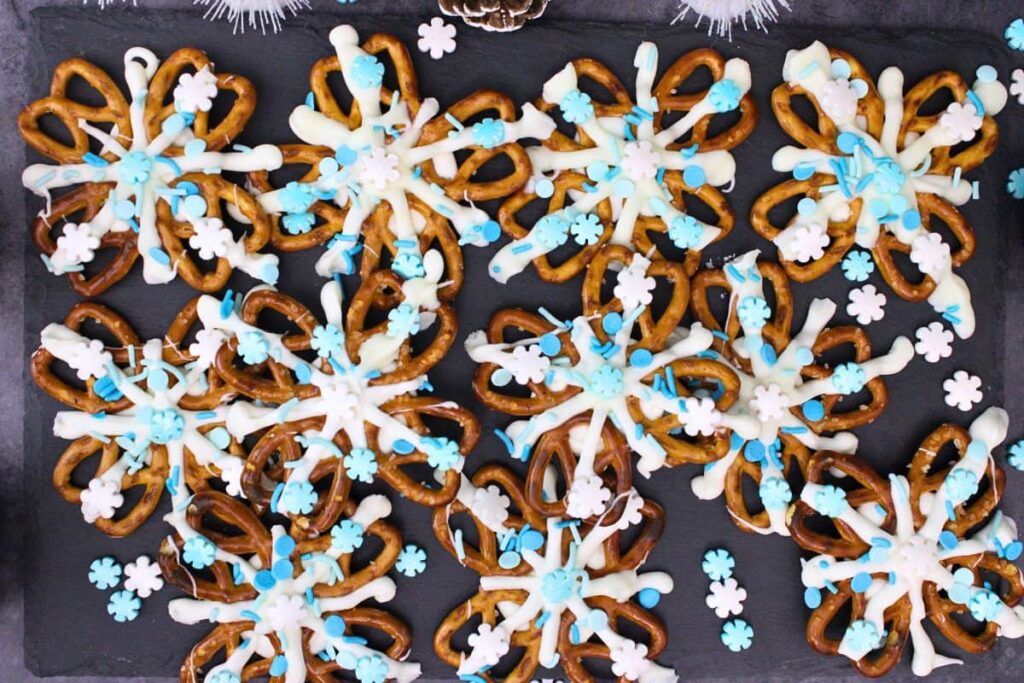 overhead view of several snowflake pretzels with sprinkles