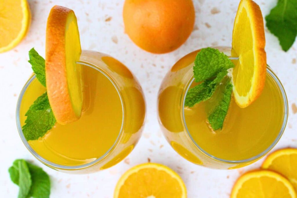 overhead view of two beermosa drinks garnished with mint and orange slices