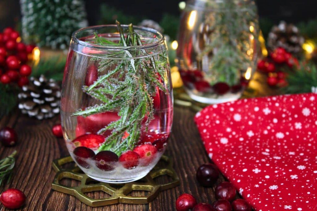 two snow globe cocktails with one in the front surrounded by winter holiday decorations