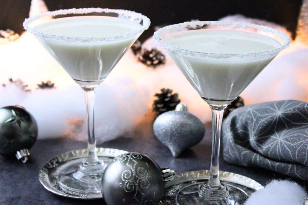 two white christmas martini drinks surrounded by classy christmas decorations