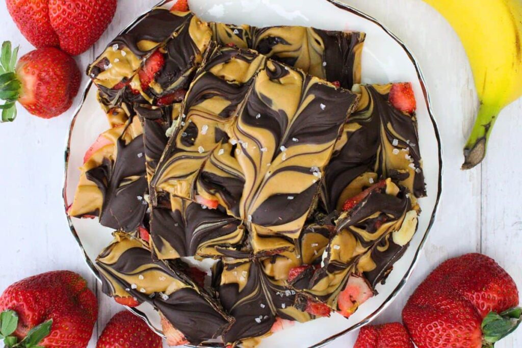 overhead view of a plate of strawberry banana bark surrounded by fresh fruit