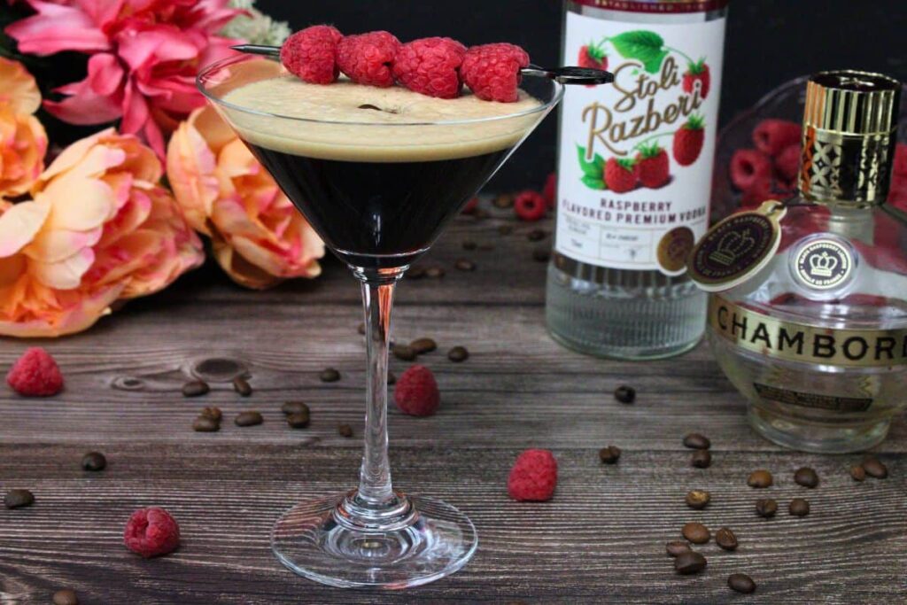 raspberry espresso martini on a wooden table next to vodka and chambord bottles