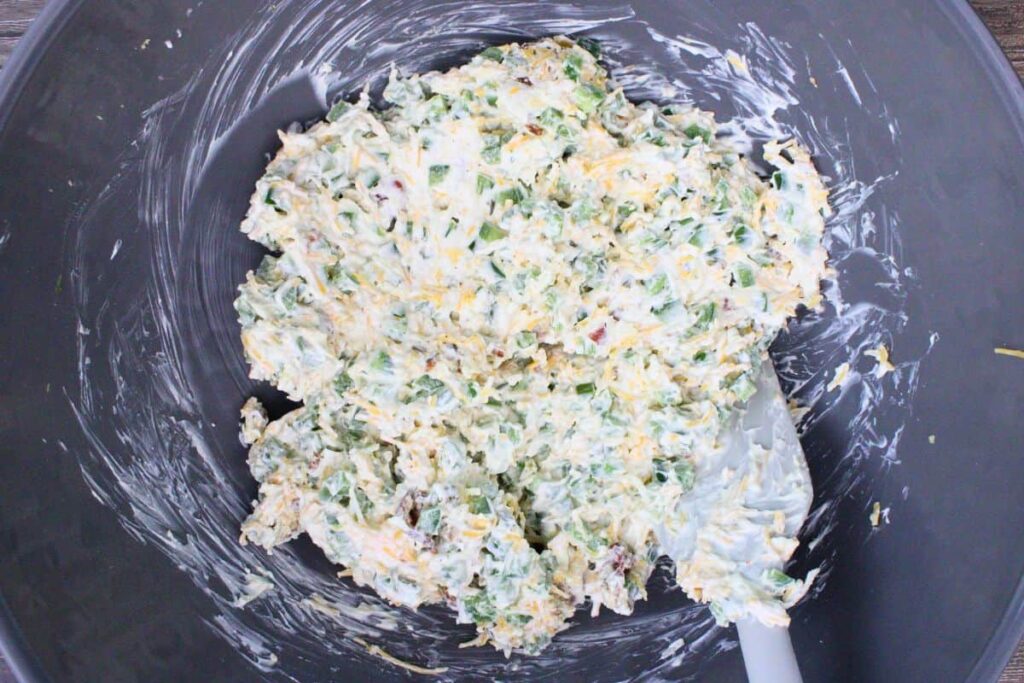 combine cream cheese, sour cream, bacon, jalapenos, garlic powder, salt, pepper, and cheddar cheese in a bowl