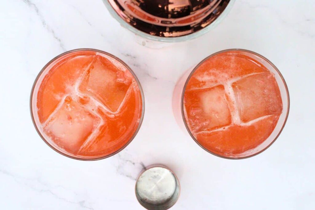 shake and strain strawberry whiskey sour into glasses
