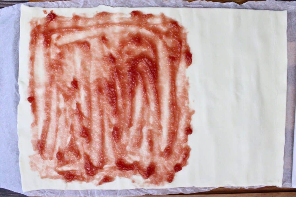 spread strawberry jam over half the puff pastry