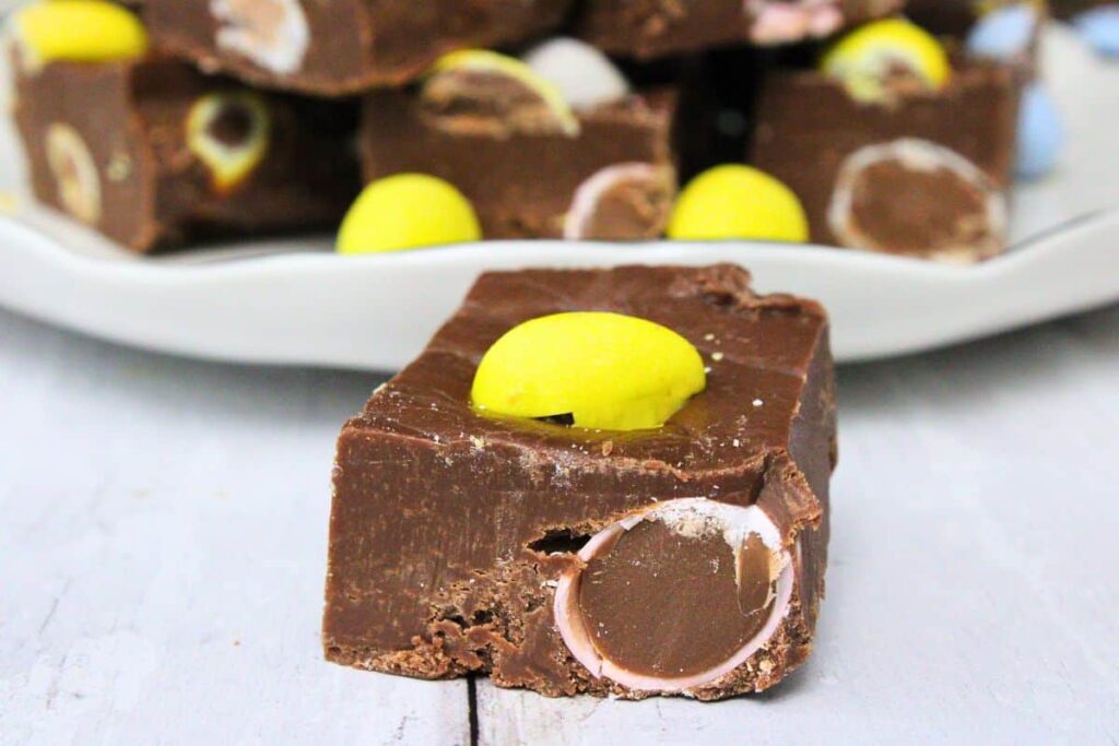 closeup of a mini egg fudge square in front of a plate of fudge