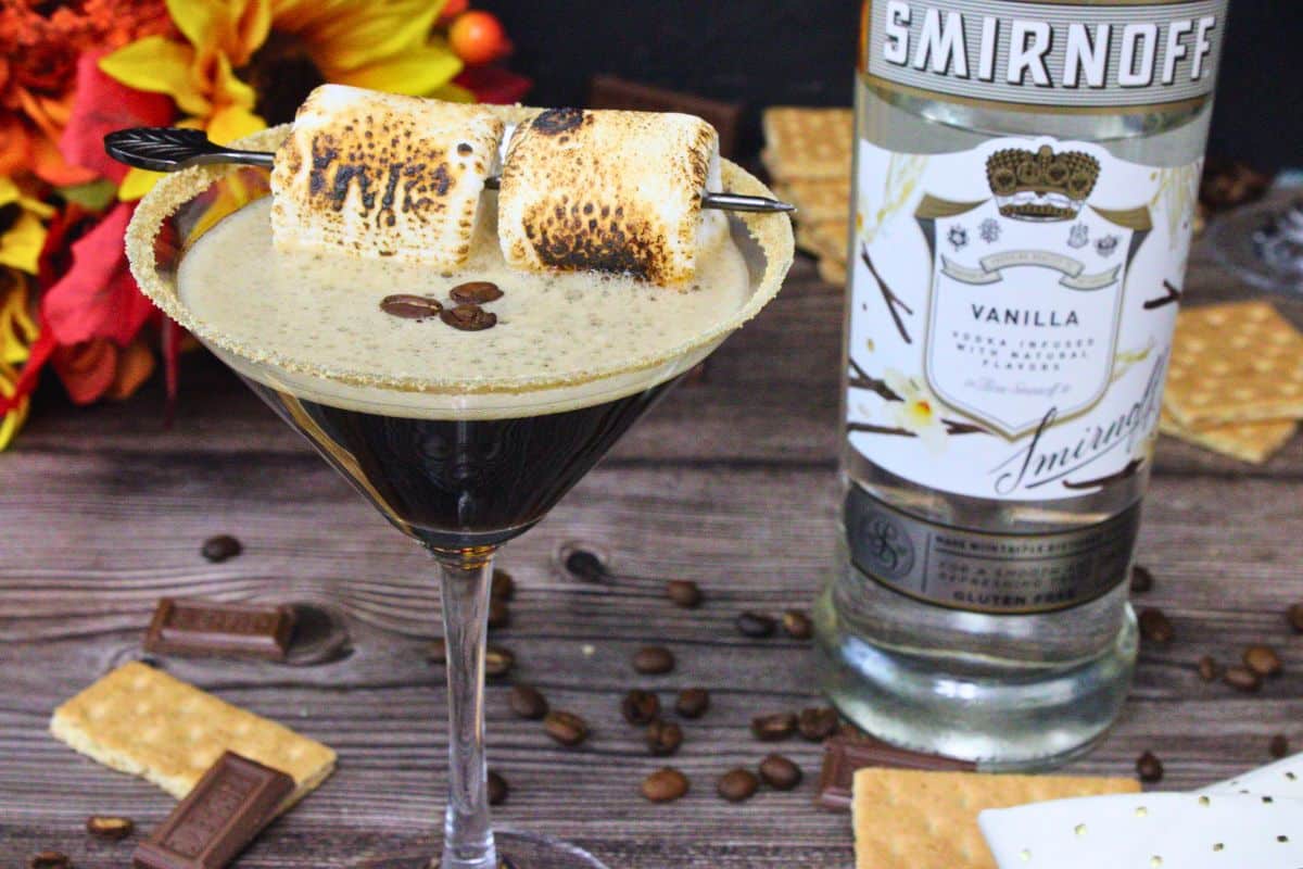 closeup view of smores espresso martini with toasted marshmallows and espresso beans next to vodka bottle