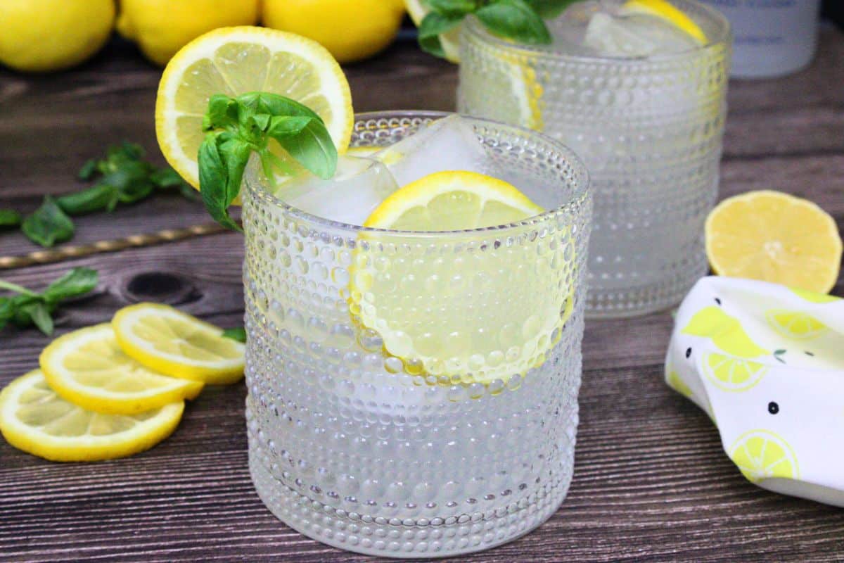 lemonade vodka punch drink garnished with lemon and basil in front of a second drink