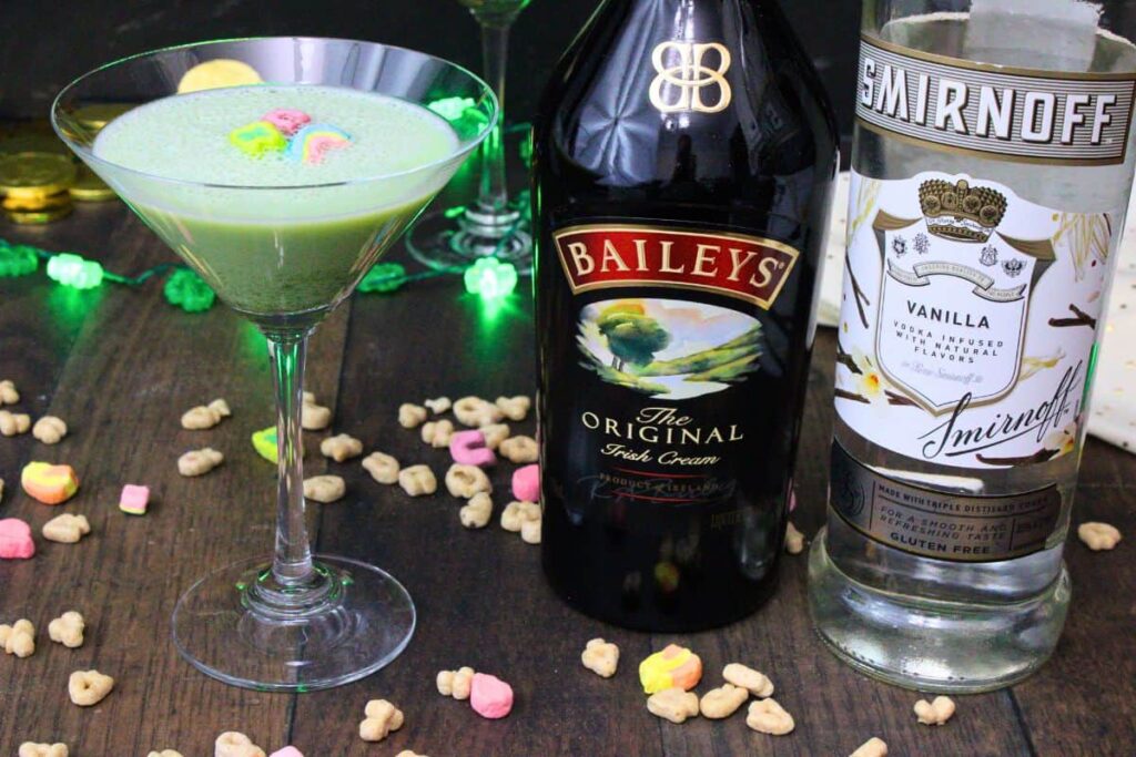lucky charms martini with three marshmallows next to baileys and vodka bottle