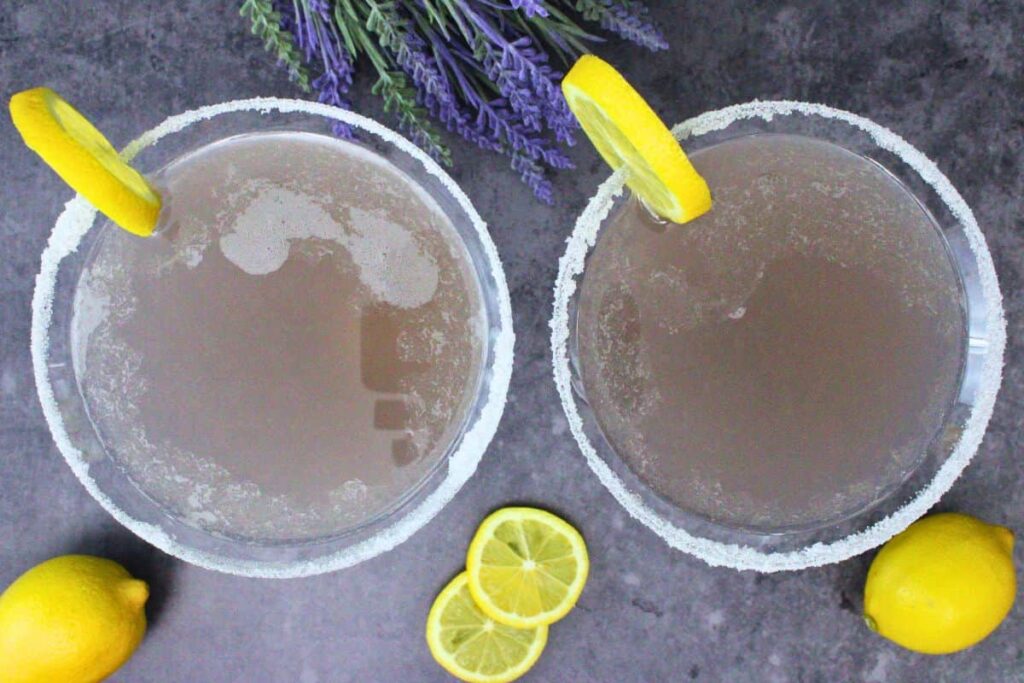 overhead view of two lavender lemon drops with a lemon slice surrounded by fresh lemons and lavender