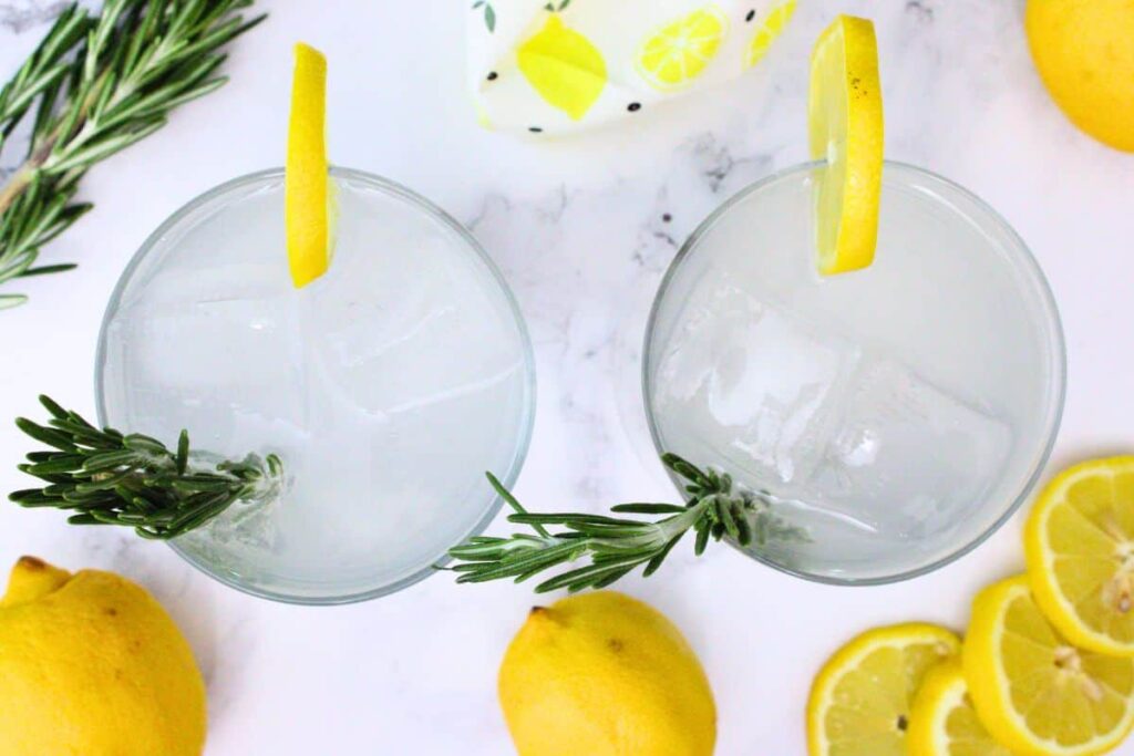overhead view of two sparkling lemonade drinks garnished with lemon and rosemary