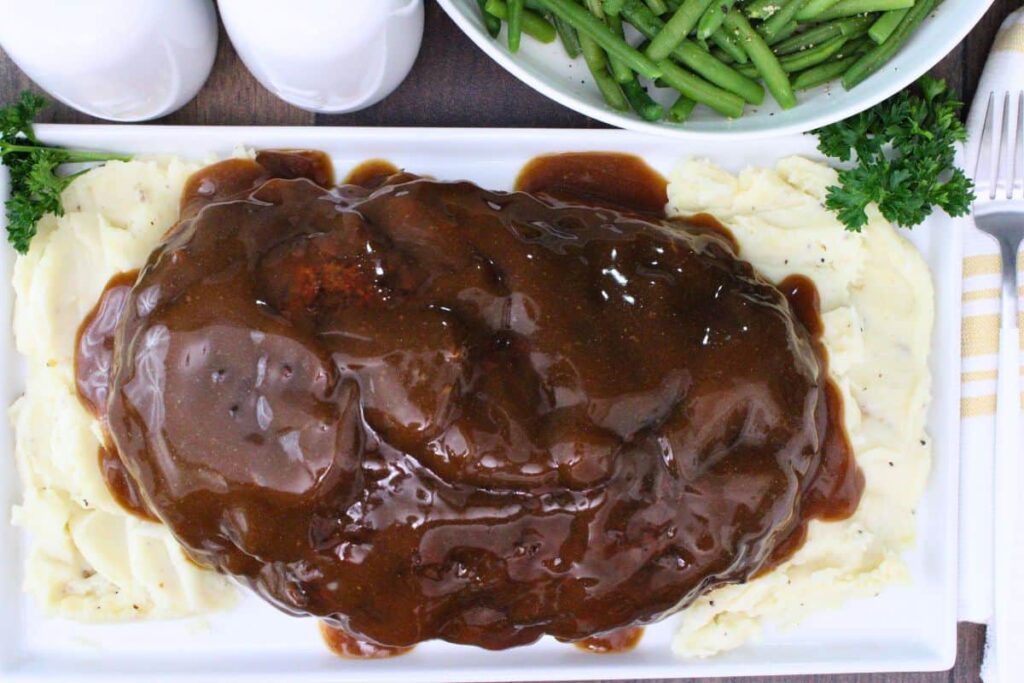 overhead view of stove top stuffing meatloag on a plate of mashed potatoes and topped with gravy