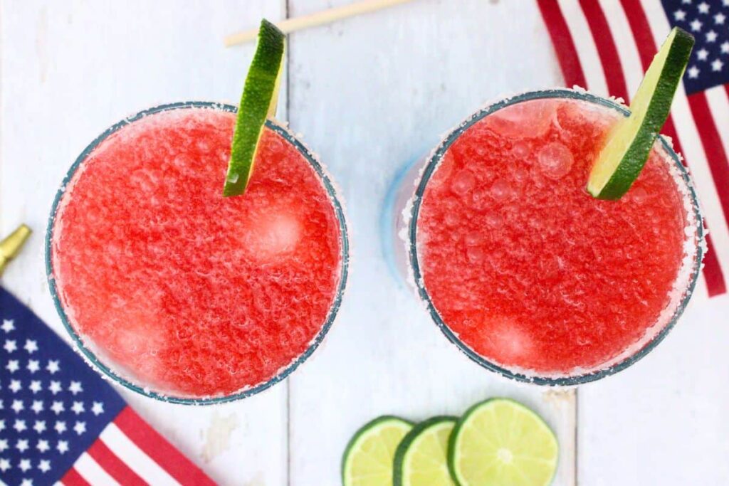 overhead view of two red white and blue margaritas garnished with lime slice and salted rim with american flags
