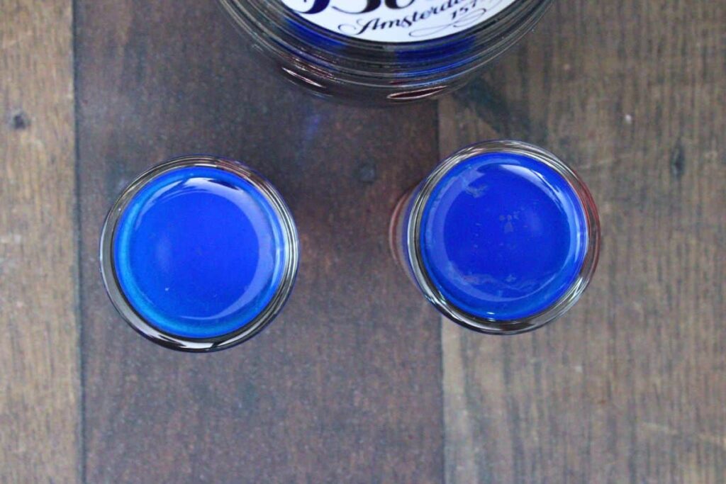 pour blue curacao over a spoon on top of white and red layers