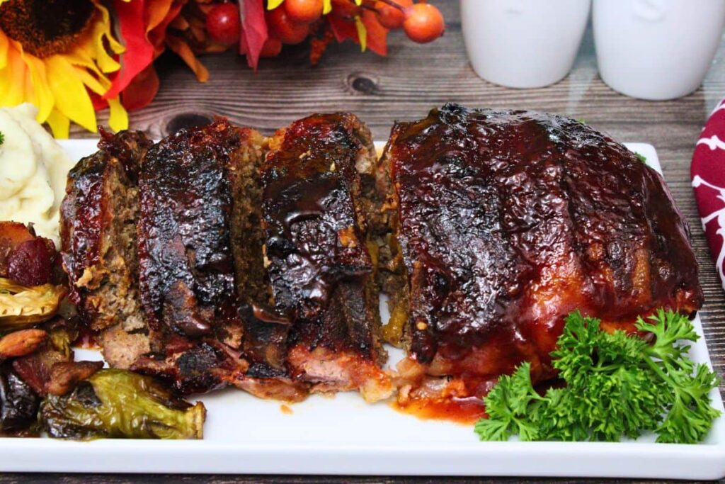 side view of a bacon wrapped meatloaf lined up and cut into slices