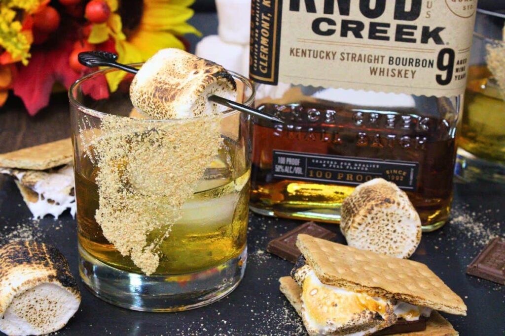 s'mores old fashioned next to bourbon bottle and smores